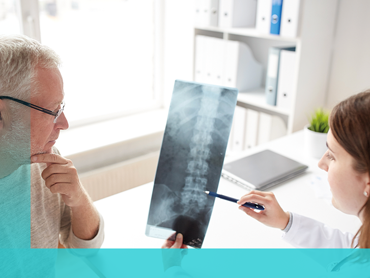Patient und Ärztin betrachten Röntgenbild von Wirbelsäule